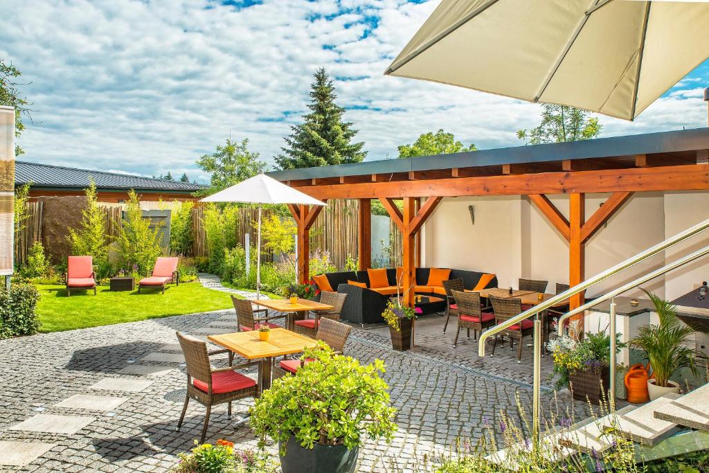 a patio with tables and chairs and an umbrella at SONN IDYLL Aparthotel in Rathenow