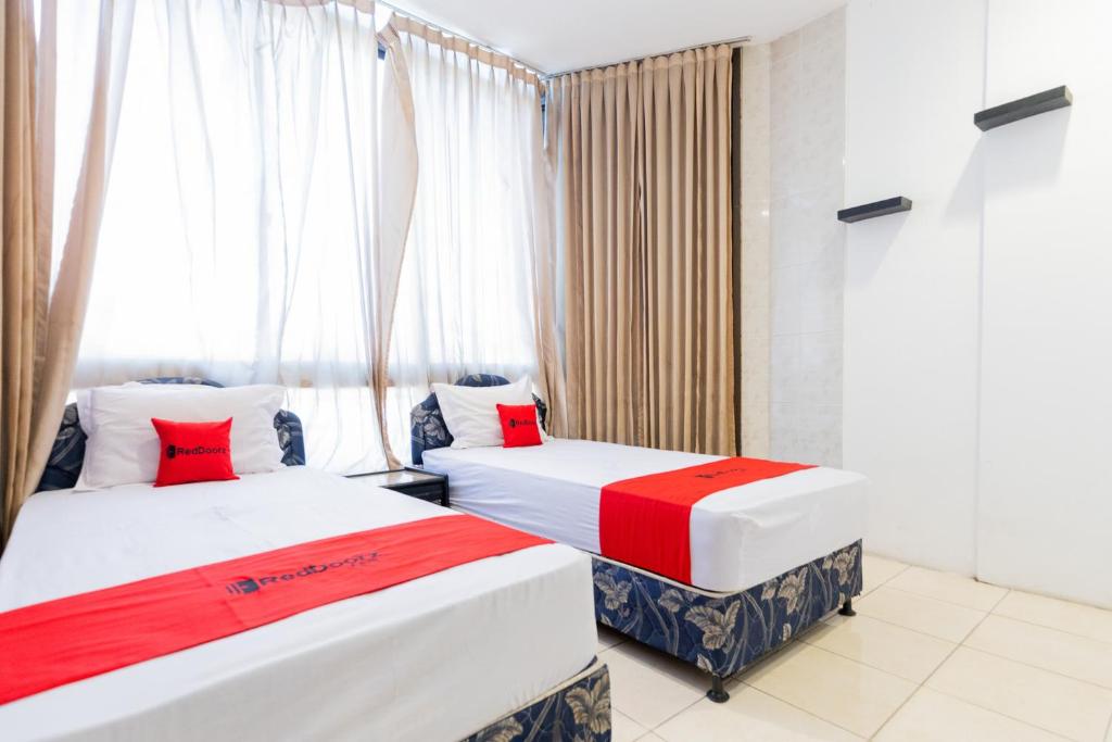 dwa łóżka w pokoju z oknem w obiekcie RedDoorz at Sparkling Hotel Surabaya w mieście Surabaja