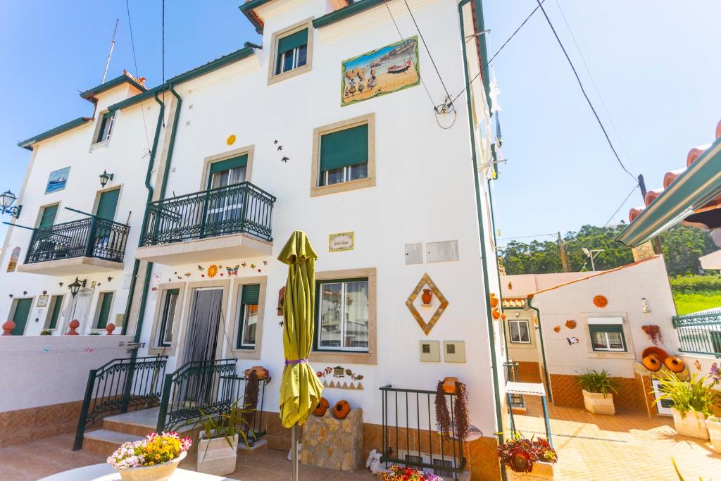 a white building with an umbrella in front of it at Moradia Valdemar in Nazaré