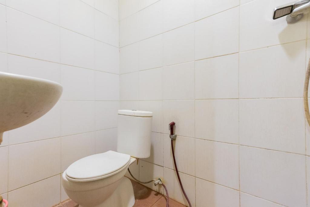 biała łazienka z toaletą i umywalką w obiekcie RedDoorz at Sparkling Hotel Surabaya w mieście Surabaja