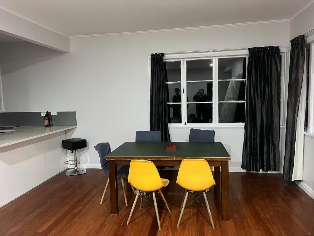 comedor con mesa y 3 sillas amarillas en 3 Bedroom House, 12 Phyllis St, Mt Albert, Auckland, en Auckland