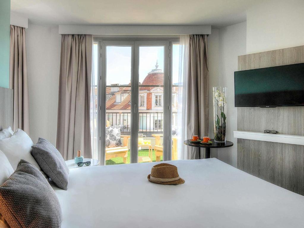 a bedroom with a white bed with a large window at Ibis Styles Nice Centre Gare in Nice