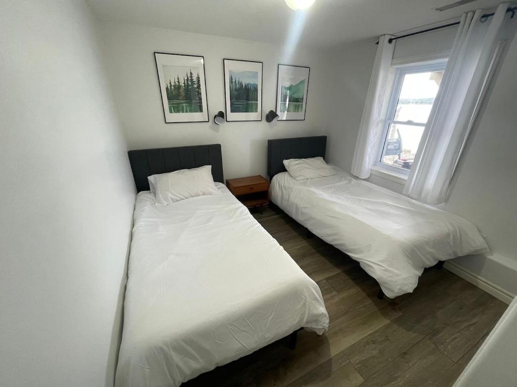 Dos camas en una habitación con dos ventanas. en Rice Lake Retreat, en Roseneath