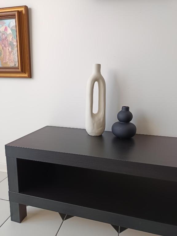 a black table with two vases on top of it at Sorella in Šabac