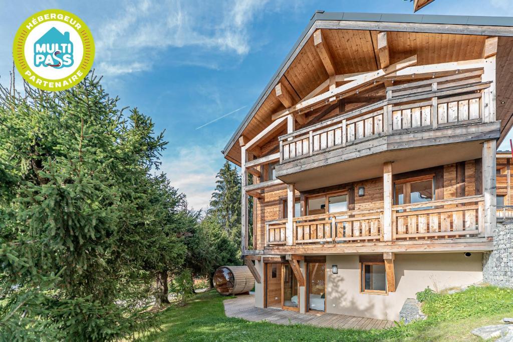 une grande maison en bois avec des arbres devant elle dans l'établissement Chalet Octopussy - LES GETS, jacuzzi, sauna, superbe vue, aux Gets