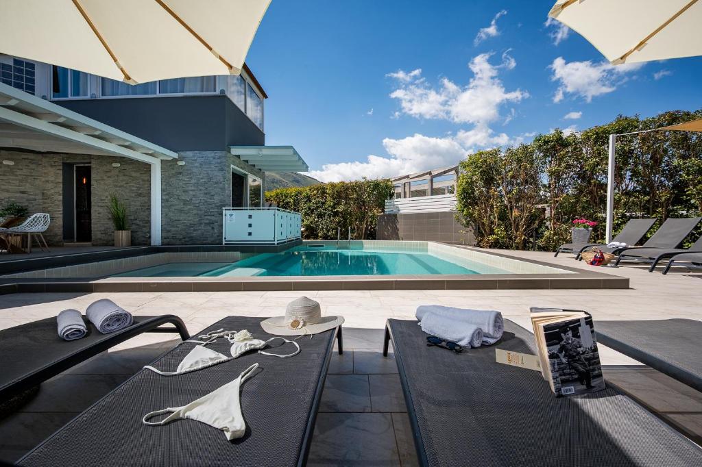 a house with a swimming pool and a table with a tablet at Moresca Exclusive Villa - Pool & Spa in Castellammare del Golfo