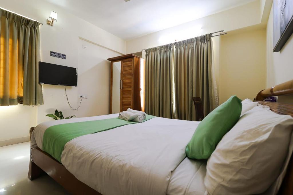 um quarto com uma cama grande e almofadas verdes em Hotel Grand View - Pimple Saudagar em Chinchwad