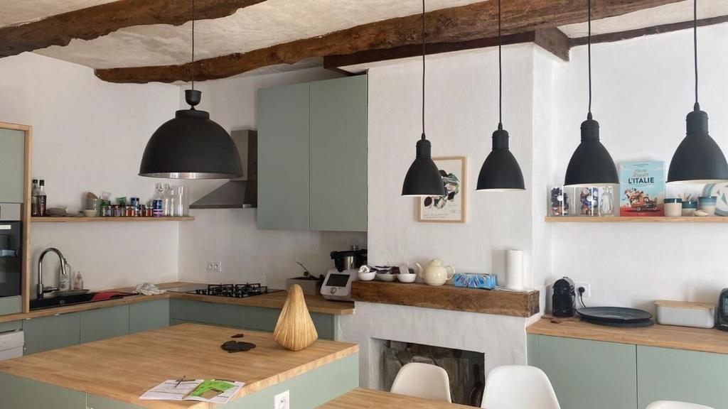 une cuisine avec des suspensions noires et une cheminée dans l'établissement Grande Capitainerie en bord de Rance, à Plouër-sur-Rance