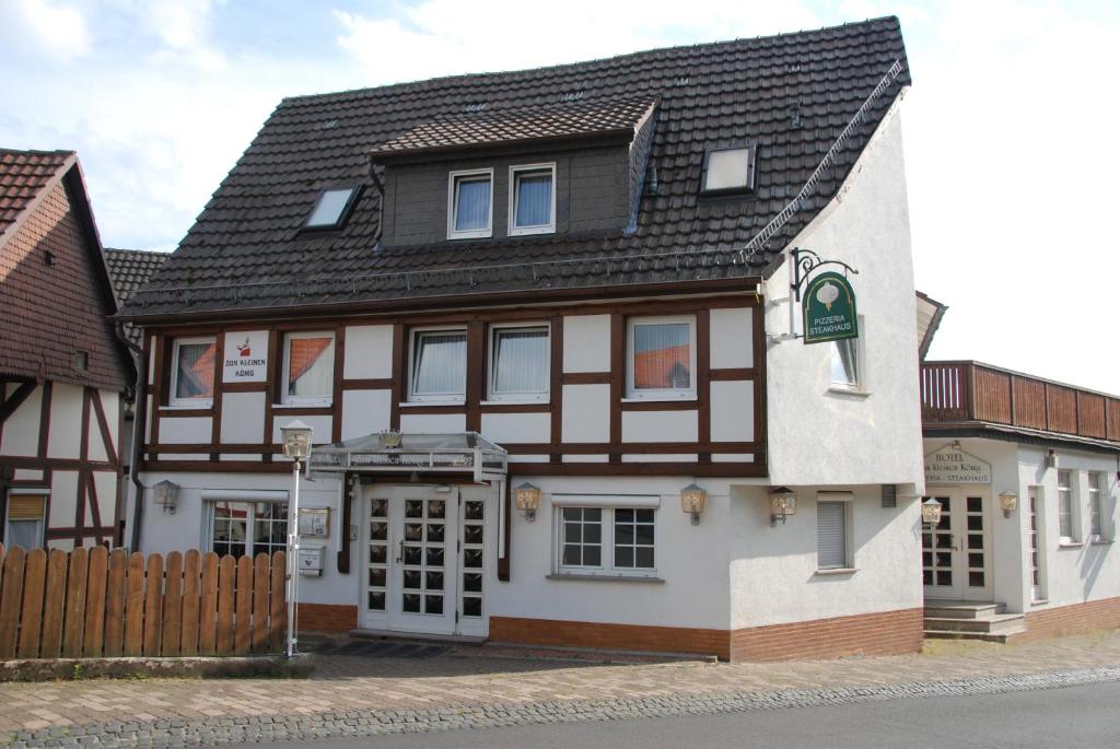 biało-brązowy budynek z czarnym dachem w obiekcie Hotel- Restaurant Zum Kleinen König w mieście Bad Zwesten