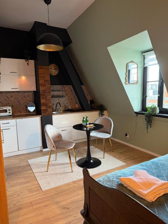 a bedroom with a table and chairs and a kitchen at Apartamenty w centrum Wawel & Smok AC Progres in Toruń