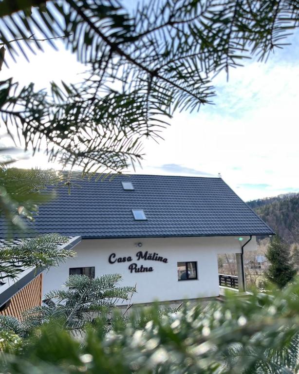 a building with a roof with the words care milking village at Casa Mălina Putna in Putnişoara
