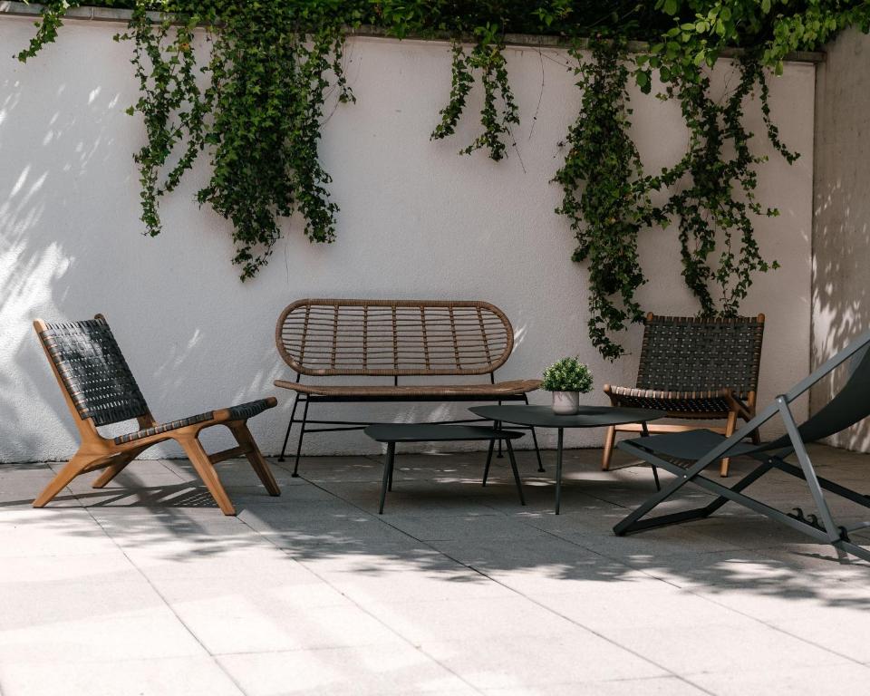 deux chaises et un banc et une table contre un mur dans l'établissement 7Hotel&Spa, à Illkirch-Graffenstaden