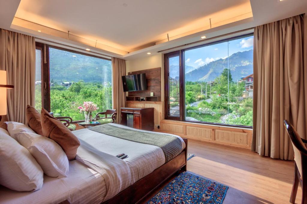 una camera da letto con un letto e una grande finestra di The Katoch Grand Resort a Manāli