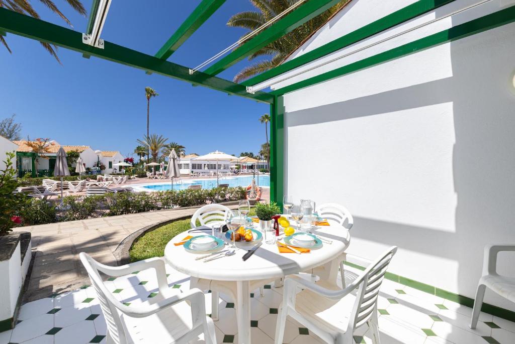 a white table and chairs on a patio with a view of the ocean at Campo Golf 75 by VillaGranCanaria in Maspalomas