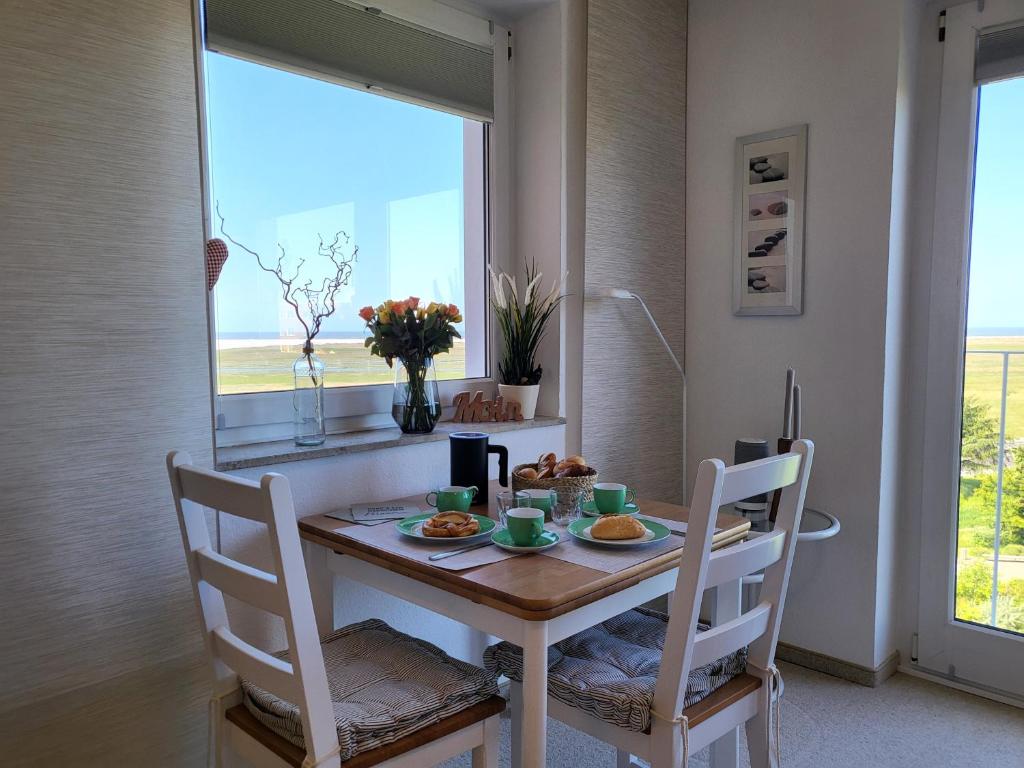 una sala da pranzo con tavolo, sedie e una finestra di DECK 7 a Sankt Peter-Ording