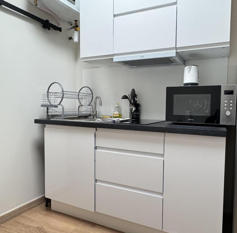 a kitchen with white cabinets and a microwave at Studio Lumineux Mezzanine à 10 minutes de Disney in Serris