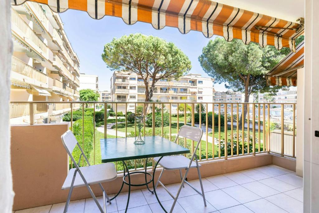 - un balcon avec une table, des chaises et des arbres dans l'établissement Studio Marco Polo Mandelieu - proche mer, à Mandelieu-la-Napoule