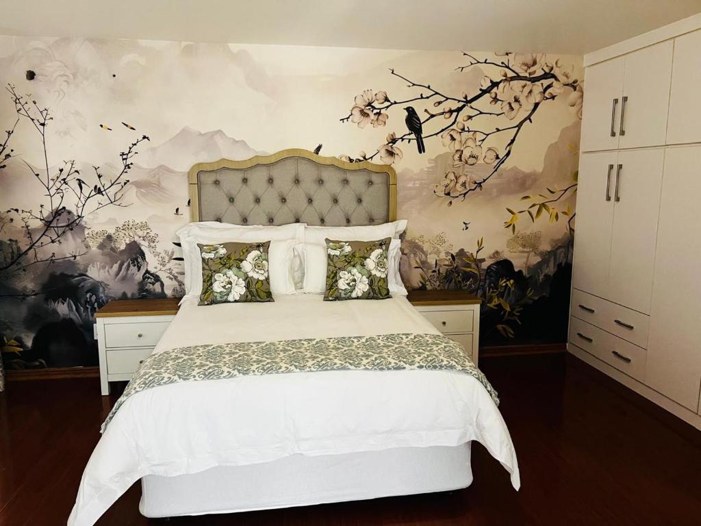 a bedroom with a white bed with a floral wallpaper at NobelAqua Suites in Maseru