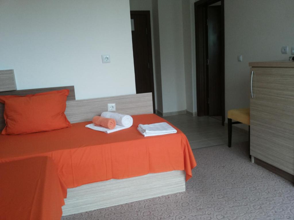 a hotel room with a bed with orange sheets and towels at Family Hotel Golden Lion in Primorsko