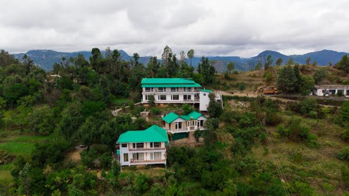 a large house with a green roof on a hill at Shree Parijat Resort - Luxury Resort in Mukteshwar in Mukteswar