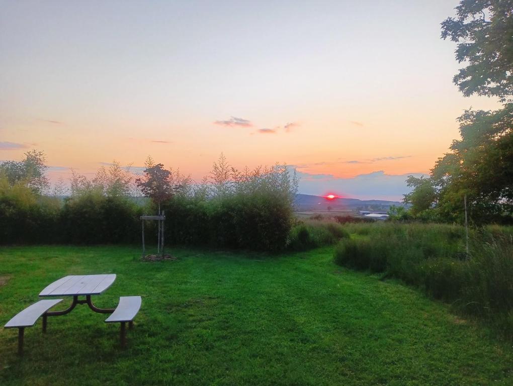 un banc dans un champ avec un coucher de soleil en arrière-plan dans l'établissement Les Arts En Ciel, à Neuvy-Grandchamp