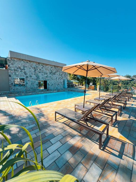 a row of benches with umbrellas next to a pool at Villa do Éden in Lindóia