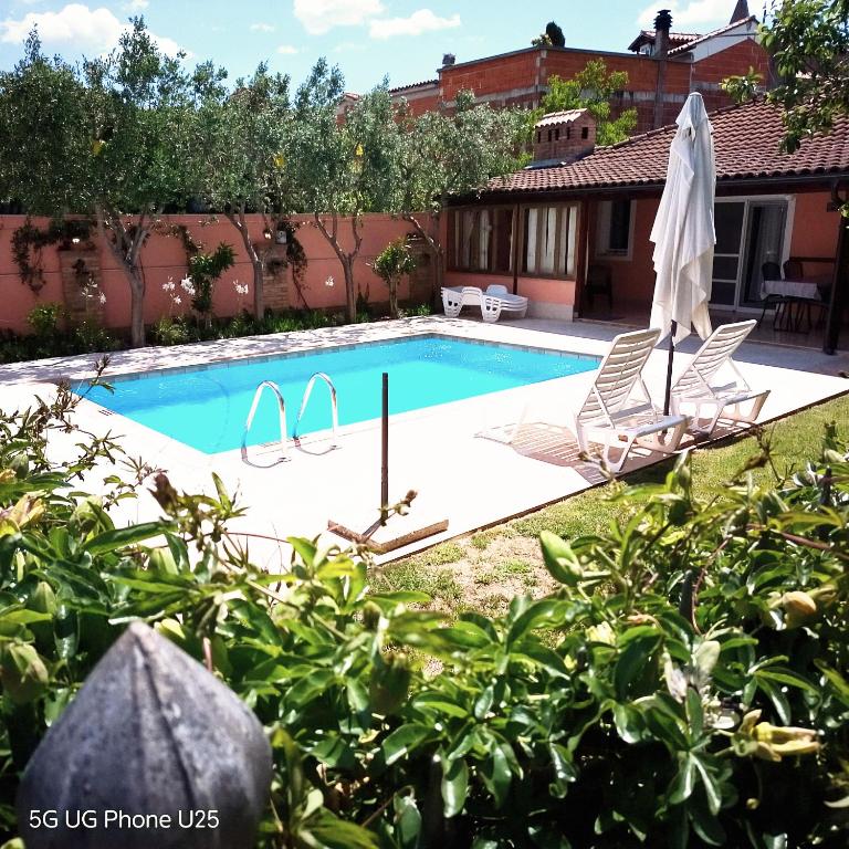a swimming pool with two chairs and an umbrella at Mario and Maria in Vodnjan