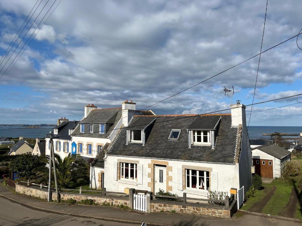 une maison blanche sur le côté d'une rue dans l'établissement Charmante maison de pêcheur bord de mer, à Plougasnou