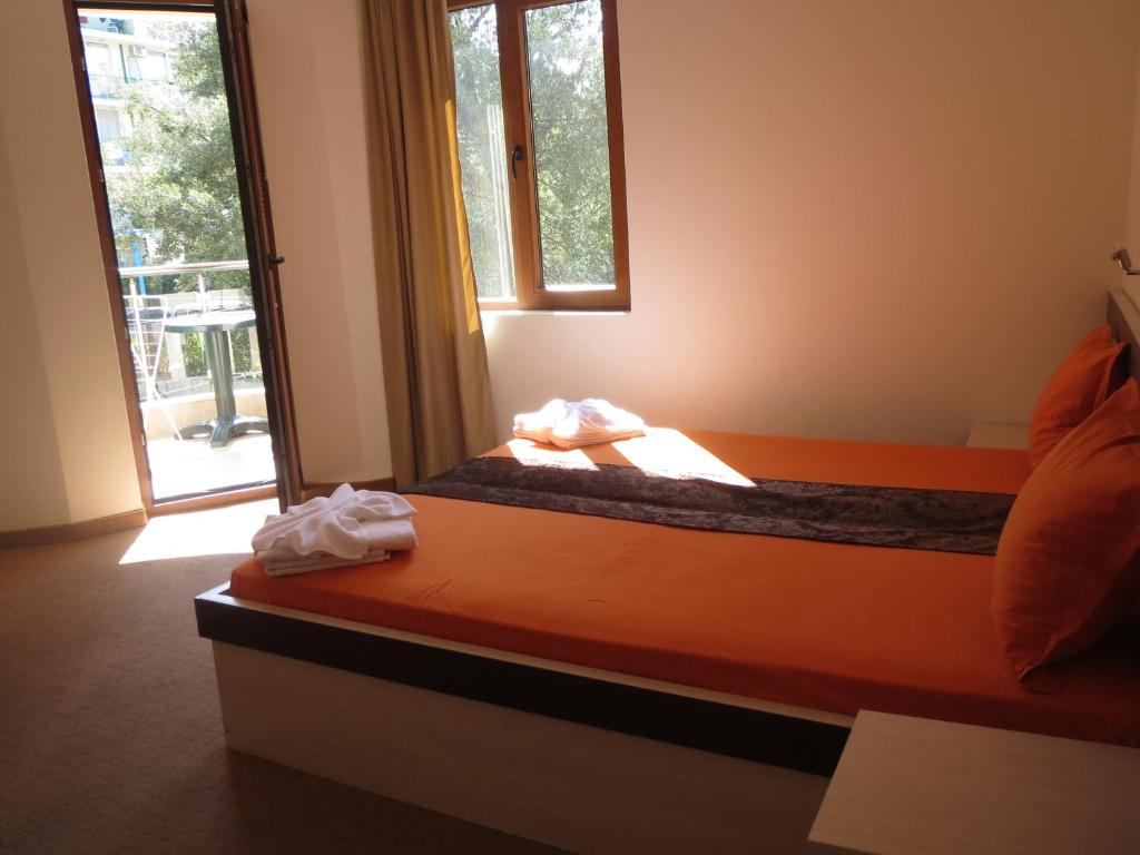 a bedroom with an orange bed with a window at Family Hotel Golden Lion in Primorsko