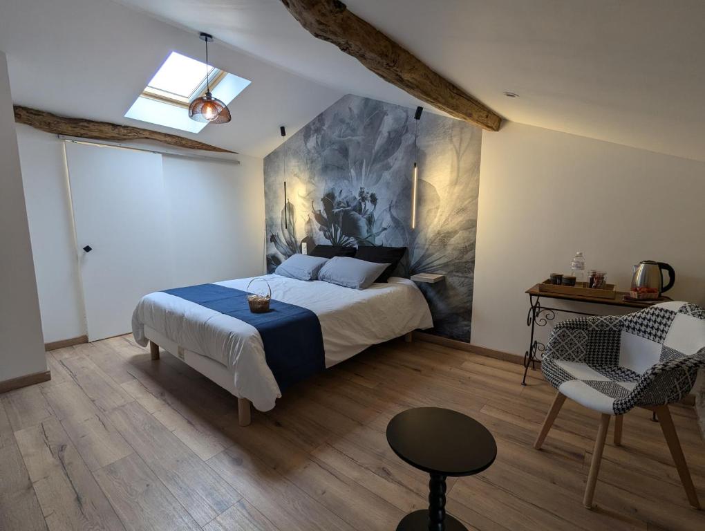 a bedroom with a bed and a table and a chair at Le refuge du Jardinier in Abzac