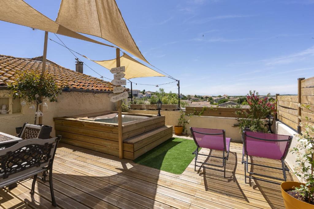 a patio with two chairs and a hot tub on a deck at Logement féerique SPA & terrasse - proche Pézenas in Abeilhan