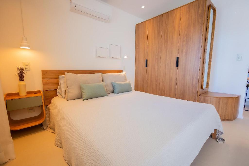 a bedroom with a white bed and a wooden cabinet at 1106 - Estúdio novíssimo com estrutura e conforto in Guarulhos
