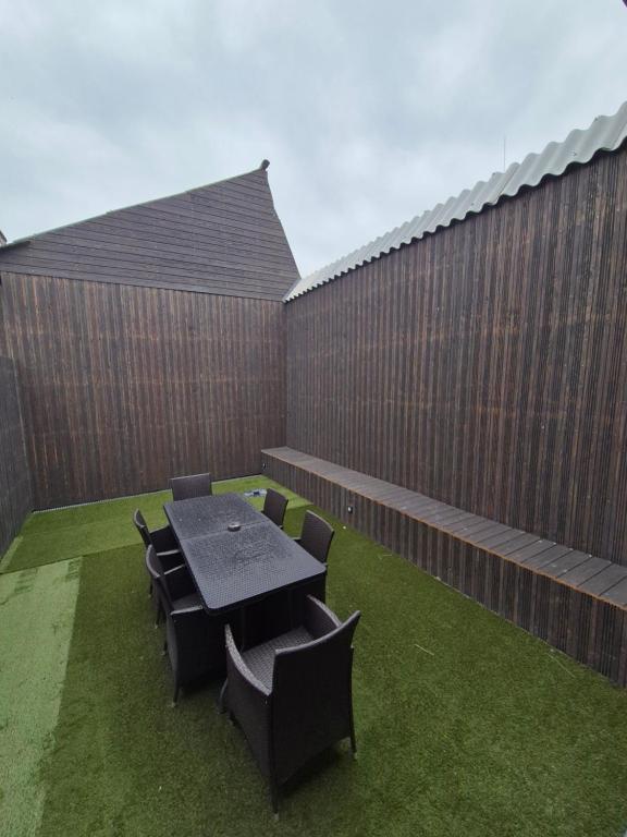 Un patio con mesa y sillas y una valla. en Gite de l'usine, en Roussay