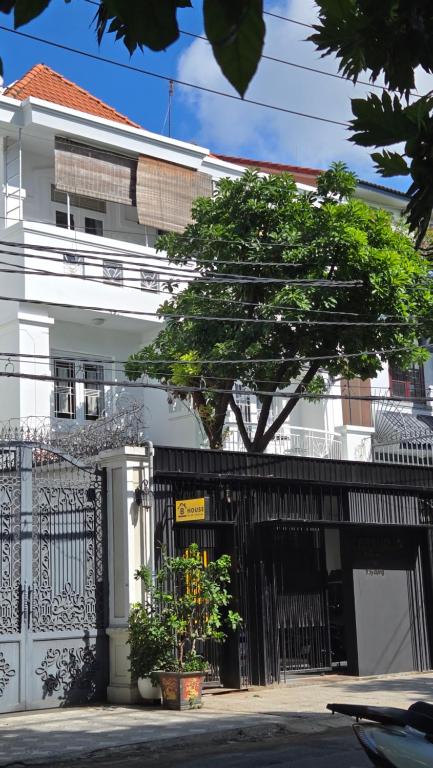 un edificio blanco con una puerta negra y un árbol en B House, en Ho Chi Minh