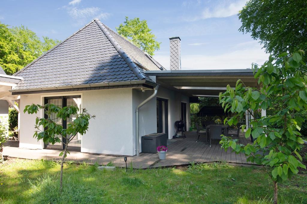 a small white house with a wooden deck at Strandhus 22 in Graal-Müritz