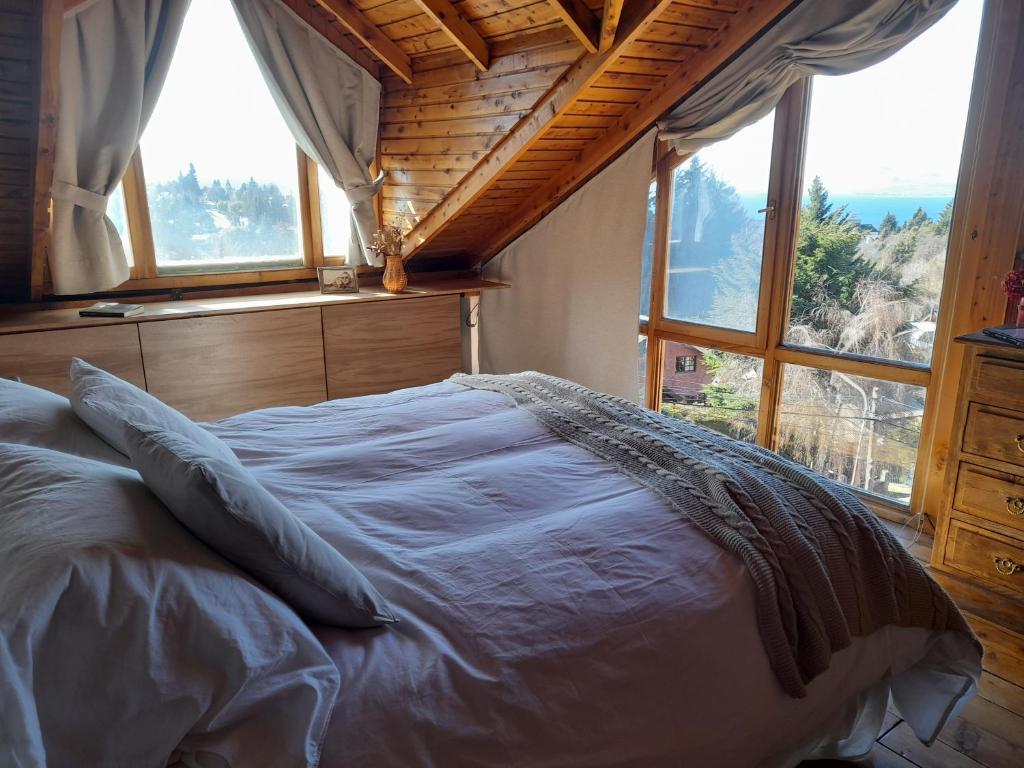 una cama en una habitación con ventana en Casa Suiza, vistas panorámicas al lago, ciudad y montañas !!, en San Carlos de Bariloche