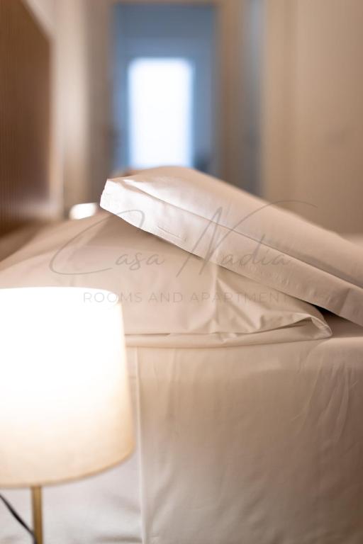 a white bed with a pillow and a lamp at Nadia Apartment in Chioggia