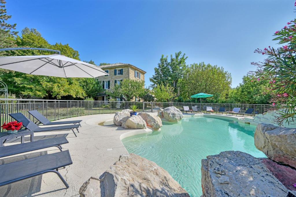 une piscine avec deux chaises et un parasol dans l'établissement La Bastide des Princes - Aile gauche, à Caderousse