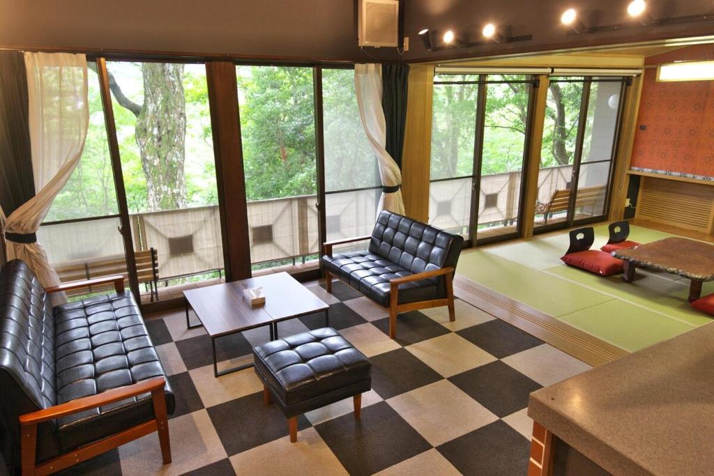 a living room with chairs and a table and windows at Y'sINN 宮城野 040H in Hakone