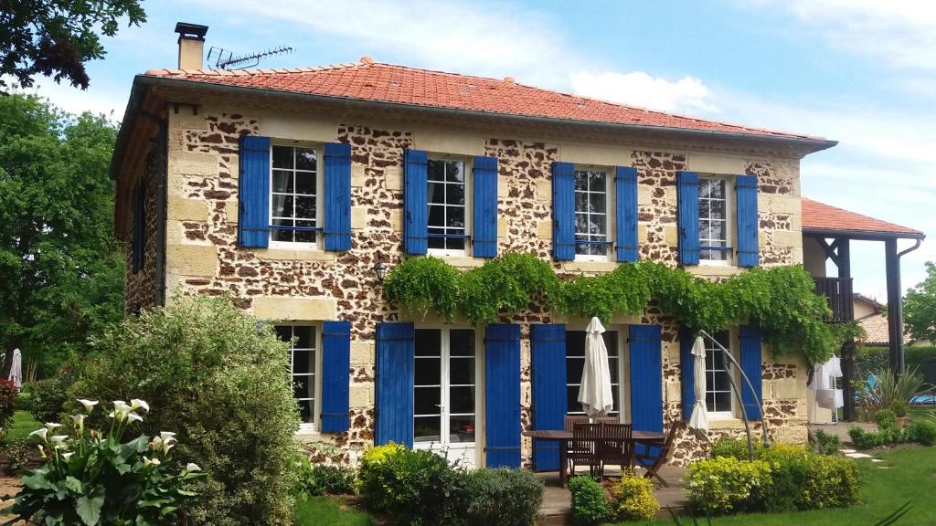 une maison avec des volets bleus et une table devant elle dans l'établissement Chambre d'Hôtes L'Airial, à Liposthey