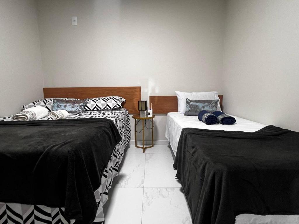two beds sitting next to each other in a room at Apartamento em Frente ao Shopping Itaguaçu in São José