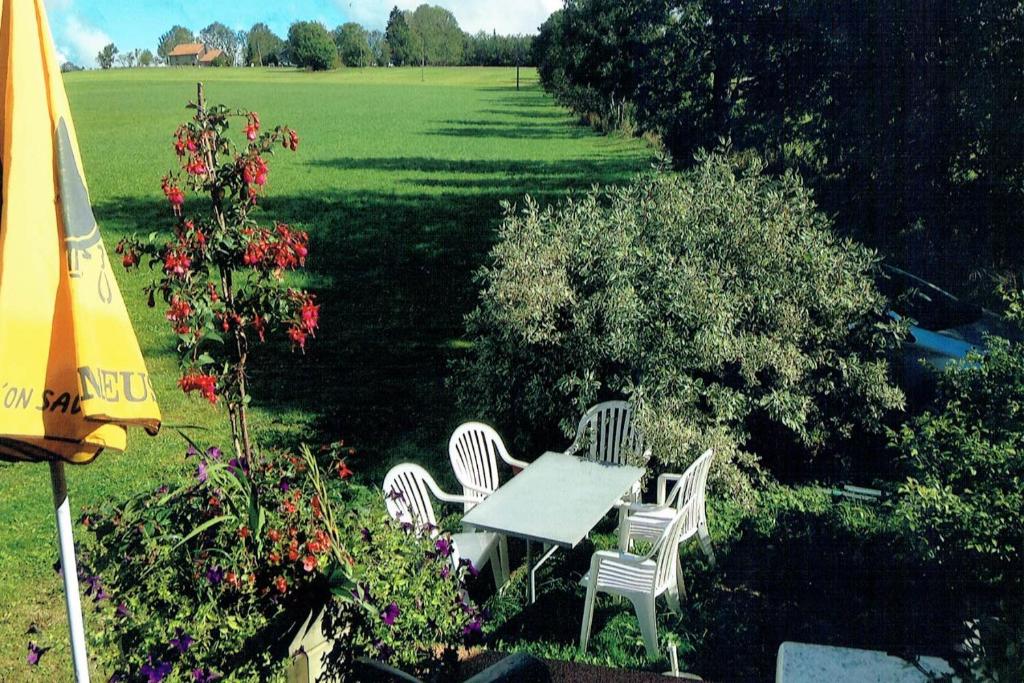 a table and chairs in a garden with an umbrella at La Clé des Champs in Les Fourgs