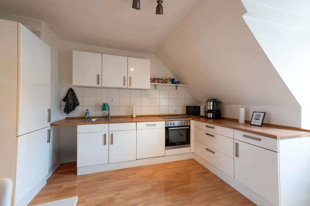 eine Küche mit weißen Schränken und Holzböden in der Unterkunft HagenStay Mittelstadt 1 in Hagen