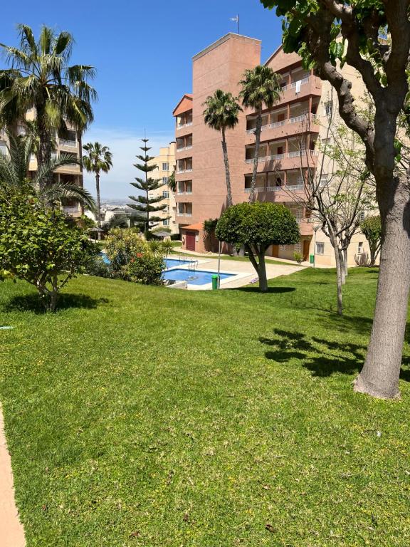 ein Park mit Gras und Bäumen und einem Gebäude in der Unterkunft Descanso y jardines con piscinas in Arenales del Sol