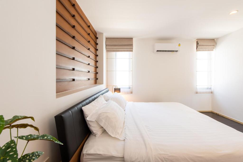 a bedroom with a white bed with a wooden headboard at Ban Talay Beach House Rayong Thailand in Ban Pak Nam Krasae