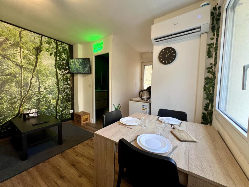 une salle à manger avec une table et une horloge murale dans l'établissement Le Jungle - Rivière - 4 Pers - Rêve au Mans, au Mans
