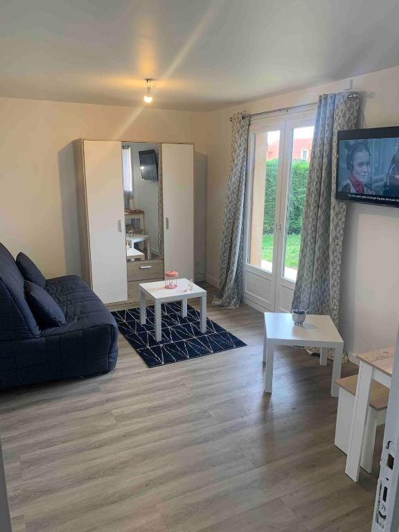 un salon avec un canapé et une télévision dans l'établissement Studio proche mer avec jardin, à Ouistreham