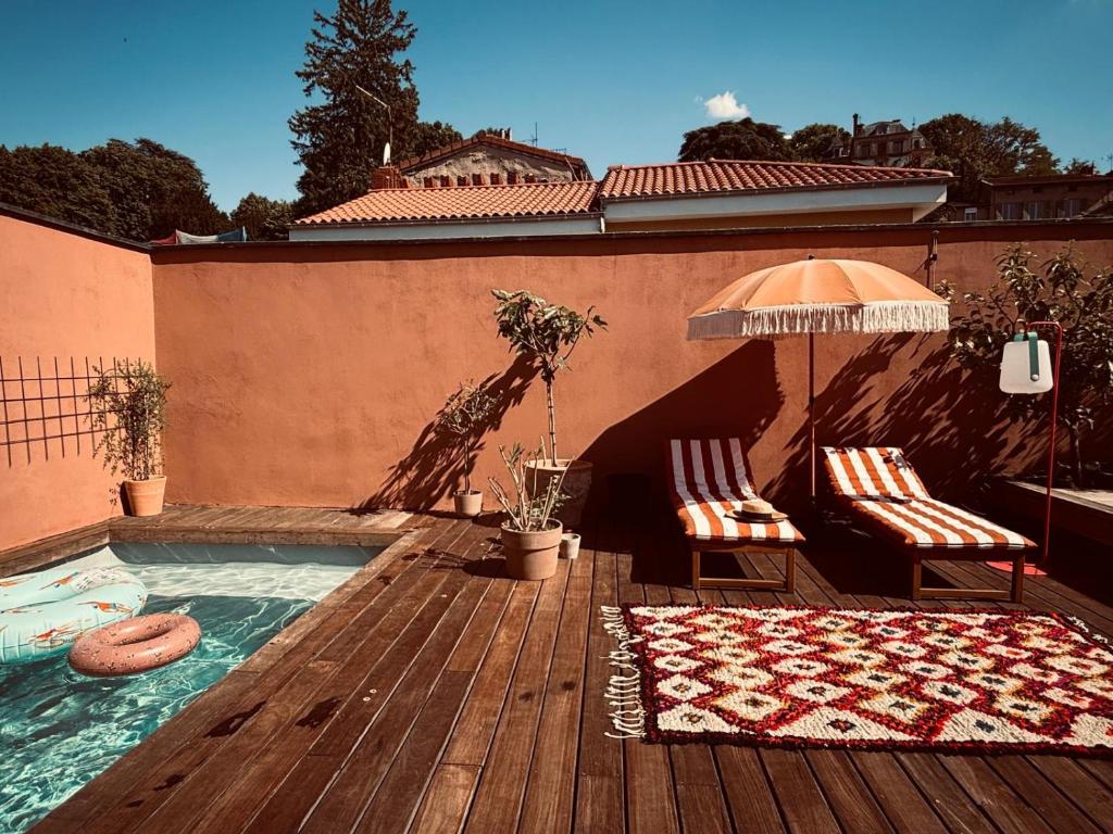 - une piscine avec 2 chaises et un parasol sur une terrasse en bois dans l'établissement La terrasse des épices, à Caluire-et-Cuire