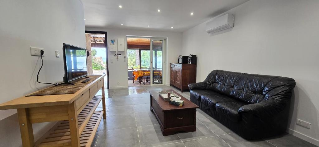 un salon avec un canapé en cuir noir et une table dans l'établissement Spacieux T3 independent air-conditioned, à Six-Fours-les-Plages