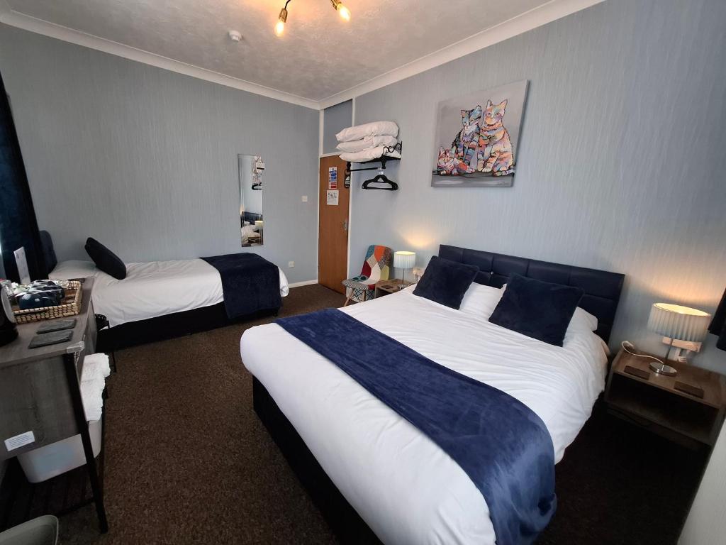 a hotel room with two beds and a television at Westbrook Lodge Guest House in Margate